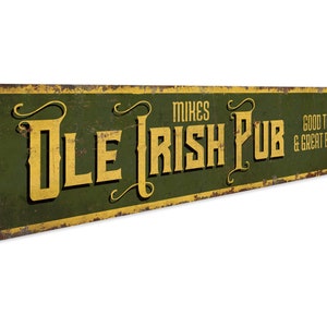 Peut inclure: Une enseigne en métal verte et dorée avec le texte "Mike's Ole Irish Pub" et la phrase "Good times & great friends".