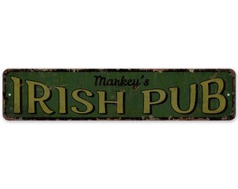 Puede incluir: Un letrero de metal verde con el texto "Markey's Irish Pub" en letras amarillas. El letrero tiene un aspecto desgastado y oxidado.