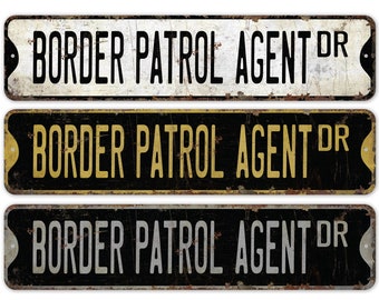 May include: Three vintage-style metal signs with the text "BORDER PATROL AGENT DR" in bold, capital letters. The signs are rectangular with rounded corners and a distressed, rusty appearance. The top sign is white, the middle is black with yellow text, and the bottom is black with silver text.