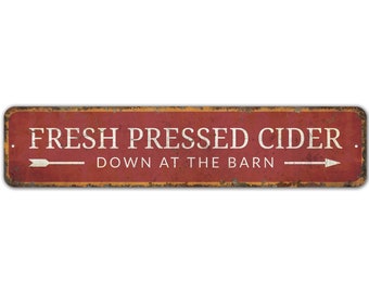 May include: A red and yellow metal sign with the text "FRESH PRESSED CIDER. DOWN AT THE BARN" and two white arrows pointing in opposite directions.