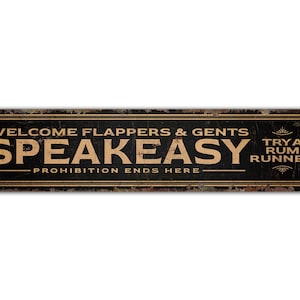 May include: A vintage-style metal sign with a black background and gold lettering. The sign reads "Welcome Flappers & Gents SPEAKEASY Prohibition Ends Here" with a smaller gold inscription on the right side that reads "Try a Rum Runner".