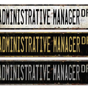 May include: Three vintage-style metal signs with the text "ADMINISTRATIVE MANAGER DR" in black lettering on a white, black, and grey background.