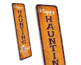 May include: Two vertical metal signs with a distressed orange background and purple text that reads "Happy Haunting". The sign on the left has a white ghost with purple eyes.