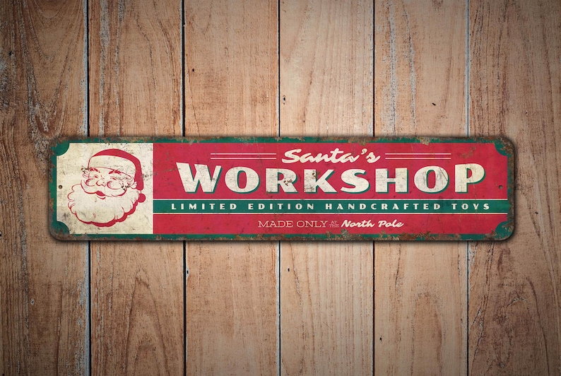 May include: Red and green metal sign with the text "Santa's Workshop" and "Limited Edition Handcrafted Toys Made Only at the North Pole". A cartoon image of Santa Claus is on the left side of the sign.