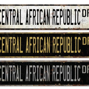 May include: Three vintage-style metal signs with the text "CENTRAL AFRICAN REPUBLIC DR" in black lettering on a white, black, and gray background. The signs have a distressed, rusty look.