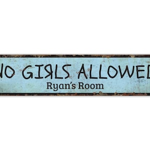 May include: A blue and brown metal sign with the text "NO GIRLS ALLOWED" and "Ryan's Room" in black lettering.