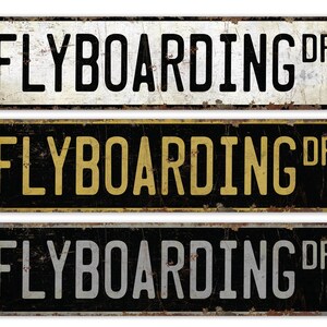 May include: Three vintage-style metal signs with the text "FLYBOARDING DR" in black, gold, and white lettering on a black, white, and black background, respectively.