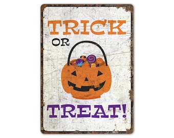 May include: A white metal sign with a distressed finish. The sign says "Trick or Treat!" with a jack-o'-lantern bucket filled with sweets in the centre.