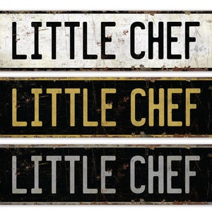 May include: Three metal signs with the text "LITTLE CHEF" in different colors. The top sign has black text on a white background. The middle sign has gold text on a black background. The bottom sign has silver text on a black background.