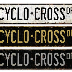 Może przedstawiać: Trzy metalowe tabliczki w stylu vintage z napisem "CYCLO-CROSS DR" w czarnych, żółtych i szarych literach na czarnym tle.