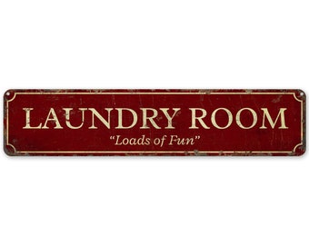 Op de afbeelding: Een rood metalen bord met witte tekst waarop "Laundry Room" en "Loads of Fun" staat.
