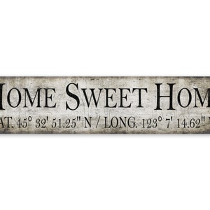 Op de afbeelding: Een rustiek houten bord met de tekst "HOME SWEET HOME" en de coördinaten "LAT. 45° 32' 51.25" N / LONG. 123° 7' 14.62" W".