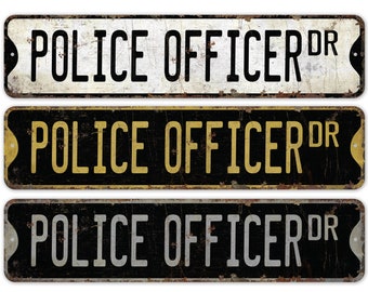 May include: Three vintage-style metal signs with the text "Police Officer Dr." in black, white, and gold lettering on a black background. The signs have a distressed, rusty look.