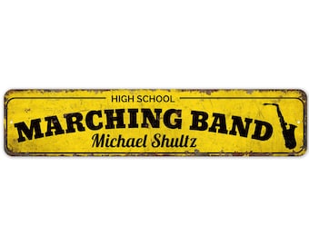 May include: Yellow metal sign with black text that reads "HIGH SCHOOL MARCHING BAND Michael Shultz" with a black silhouette of a saxophone on the right side.