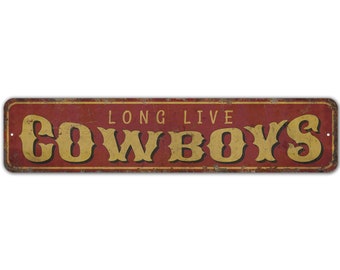 Peut inclure: Une plaque en métal rouge avec une finition vieillie. La plaque porte l'inscription "Long Live Cowboys" en lettres jaunes.