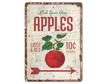 May include: Vintage-style metal sign with a distressed white background and red text. The sign reads "Pick Your Own Apples" with a red apple and green leaves. The text "Crisp & Red" and "10¢ a basket" is also included.