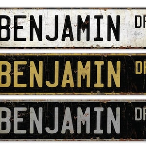 May include: Three vintage-style metal street signs with the name "Benjamin Dr." in black, gold, and silver lettering on a black background.