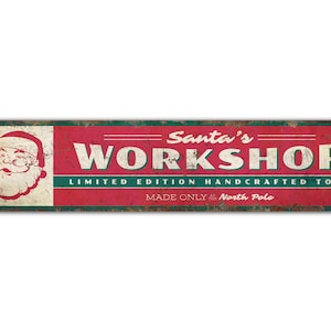 May include: A red and green vintage-style metal sign with the text "Santa's Workshop. Limited Edition Handcrafted Toys. Made Only at the North Pole." and a cartoon image of Santa Claus.