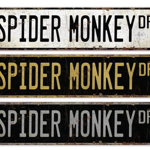 May include: Three vintage-style metal signs with the text "Spider Monkey Dr." in black, gold, and white lettering on a black, white, and black background, respectively.
