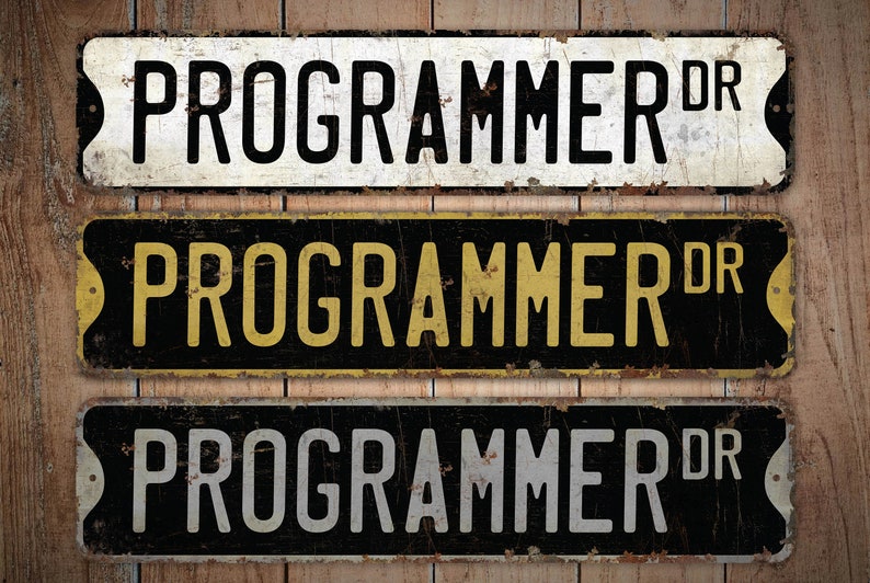 K&ouml;nnte beinhalten: Drei Schilder im Vintage-Stil aus Metall mit dem Text "PROGRAMMER DR" in schwarzer, goldener und wei&szlig;er Schrift auf schwarzem Hintergrund. Die Schilder haben ein abgenutztes, rostiges Aussehen.