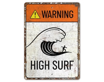 May include: A white metal sign with a distressed look. The sign has an orange warning sign at the top with an exclamation point and the word "WARNING". Below the warning sign is a black and white illustration of a surfer riding a large wave. The text "HIGH SURF" is printed in black at the bottom of the sign.