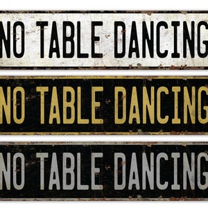 May include: Three rectangular metal signs with the text "NO TABLE DANCING" in bold, white, and yellow lettering. The signs have a distressed, vintage look with rust and wear.