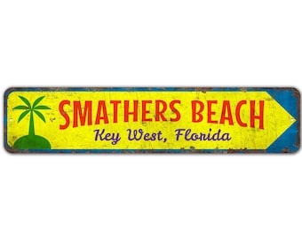 Può includere: Un cartello in metallo di stile vintage giallo e blu con una grafica di palma e il testo "SMATHERS BEACH Key West, Florida".