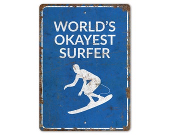 May include: A blue metal sign with a white silhouette of a surfer and the text "WORLD'S OKAYEST SURFER".
