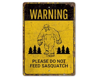 May include: Yellow warning sign with black text and a cartoon image of Bigfoot. The sign reads "WARNING PLEASE DO NOT FEED SASQUATCH".
