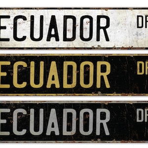 May include: Three vintage-style metal street signs displaying "ECUADOR" in bold lettering. The signs are rectangular with rounded corners and a distressed, rusty finish. The top sign is white with black text, the middle is black with yellow text, and the bottom is black with silver text.