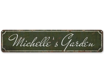 May include: A rustic green metal sign with white lettering that reads "Michelle's Garden".