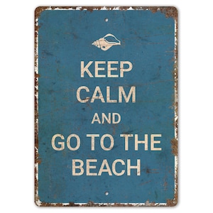 May include: A blue metal sign with a distressed, vintage look. It reads "Keep Calm and Go To The Beach" with a seashell graphic at the top.