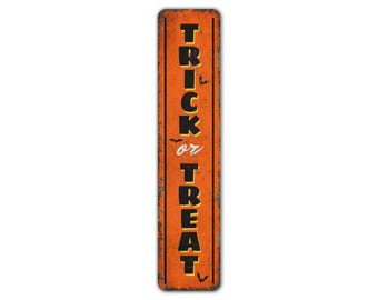 May include: Orange metal sign with the text "Trick or Treat" in black letters with a white outline. The sign has a distressed look and features small black bats.