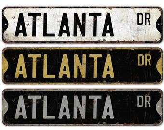 Könnte beinhalten: Drei Vintage-Metallschilder mit dem Text "ATLANTA DR" in schwarzer Schrift auf weißem, gelbem und grauem Hintergrund. Die Schilder sind verwittert und haben einen abgenutzten Look.