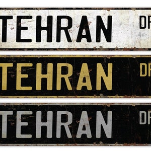 May include: Three vintage-style metal street signs with the text "TEHRAN DR" in black, gold, and silver lettering on a black background.