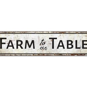 May include: White metal sign with black text that reads "FARM to TABLE".