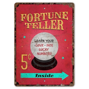 May include: A vintage-style metal sign with a red background and a yellow border. The sign reads "Fortune Teller" in large yellow letters. A crystal ball with the text "Learn Your: Love, Fate, Lucky Numbers!" is depicted in the center. The sign also includes the text "5¢ Inside" with a turquoise arrow pointing to the right.