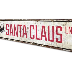 a sign that says santa claus in red on a white background
