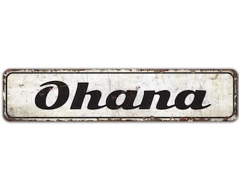 Puede incluir: Un letrero de metal blanco con textura oxidada y letras negras que dice "Ohana".