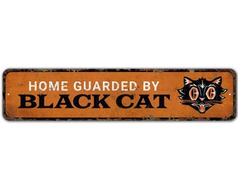 May include: A rusty orange metal sign with the text "Home Guarded By Black Cat" in white and black lettering. A black cat with orange eyes and a tongue sticking out is on the right side of the sign.
