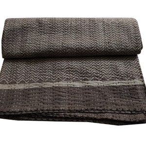 May include: A brown and white kantha quilt with a chevron pattern. The quilt has a white border and is folded in half.