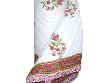 May include: White cotton quilt with a pink and green floral print. The quilt is rolled up and has a decorative border.