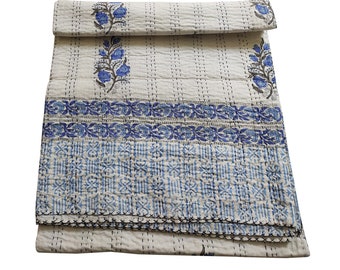 May include: A white cotton kantha quilt with a blue floral pattern. The quilt is folded in thirds and has a stitched border.