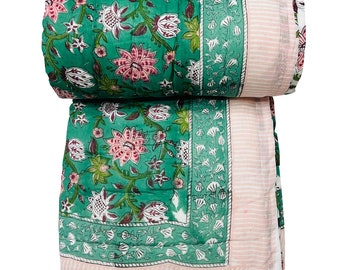 Può includere: Un trapunta di cotone floreale verde e rosa con un bordo a righe rosa e bianco. La trapunta è arrotolata e piegata a metà.