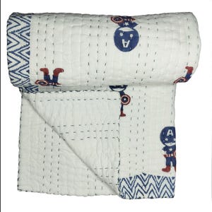 May include: White cotton quilt with a blue and red Captain America design. The quilt features a repeating pattern of Captain America figures and a blue zigzag border. The quilt is hand-stitched with navy thread.