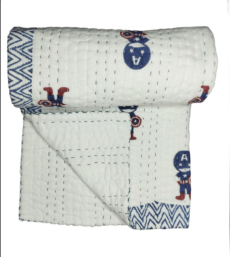 May include: White cotton quilt with a blue and red Captain America design. The quilt features a repeating pattern of Captain America figures and a blue zigzag border. The quilt is hand-stitched with navy thread.