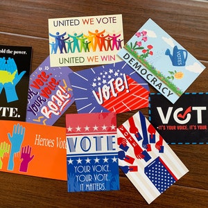 May include: A collection of colorful postcards with voting-themed designs. The cards feature phrases like "Vote," "Democracy," and "Your Voice Matters." Graphics include hands, stars, and the American flag, promoting civic engagement.