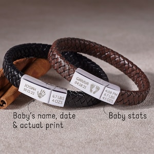 Puede incluir: Dos pulseras de cuero con placas de plata grabadas. Una pulsera es de cuero marr&oacute;n y la otra de cuero negro. Las placas incluyen los nombres "Gianna" y "Josiah", las fechas y las huellas de los pies. Las placas tambi&eacute;n incluyen el peso del beb&eacute; y la hora de nacimiento.