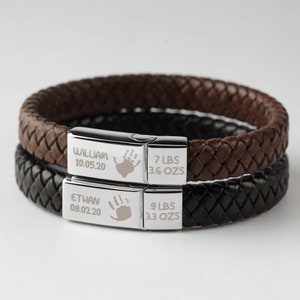 Puede incluir: Dos pulseras de cuero con placas grabadas en plata. La placa superior dice "William 10.05.20 7 LBS 3.6 OZs". La placa inferior dice "Ethan 08.02.20 9 LBS 3.3 OZs".