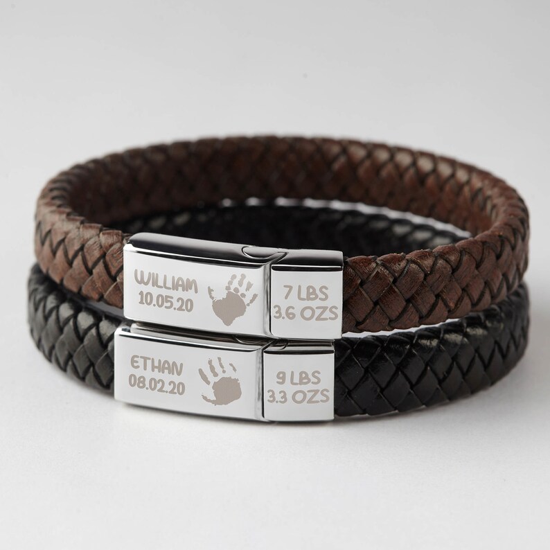 Puede incluir: Dos pulseras de cuero con placas grabadas en plata. La placa superior dice "William 10.05.20 7 LBS 3.6 OZs". La placa inferior dice "Ethan 08.02.20 9 LBS 3.3 OZs".